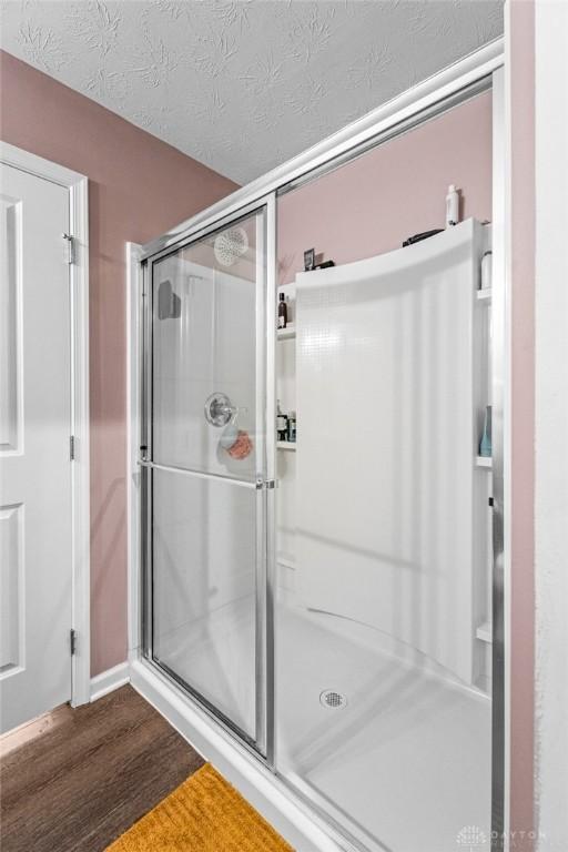 bathroom with a textured ceiling, wood-type flooring, and walk in shower