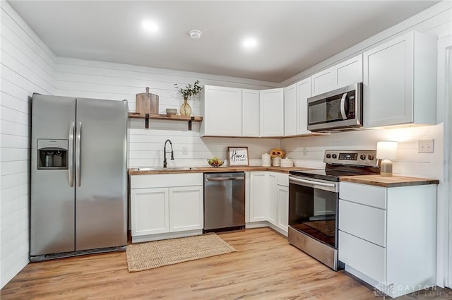 kitchen featuring sink, butcher block countertops, light hardwood / wood-style floors, white cabinets, and appliances with stainless steel finishes