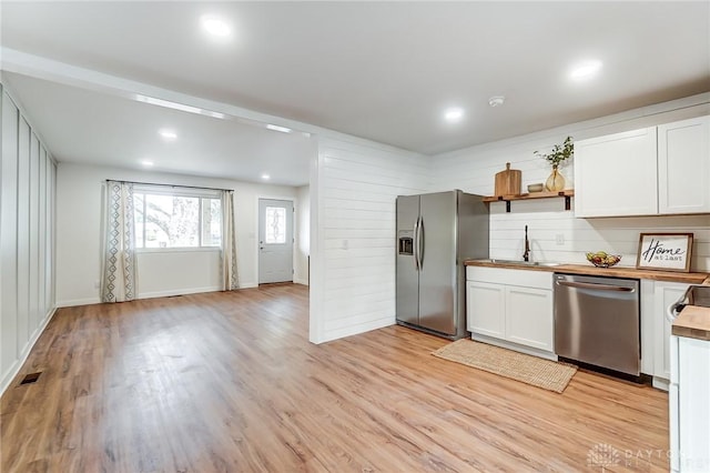 kitchen with wood counters, sink, light hardwood / wood-style flooring, appliances with stainless steel finishes, and white cabinetry