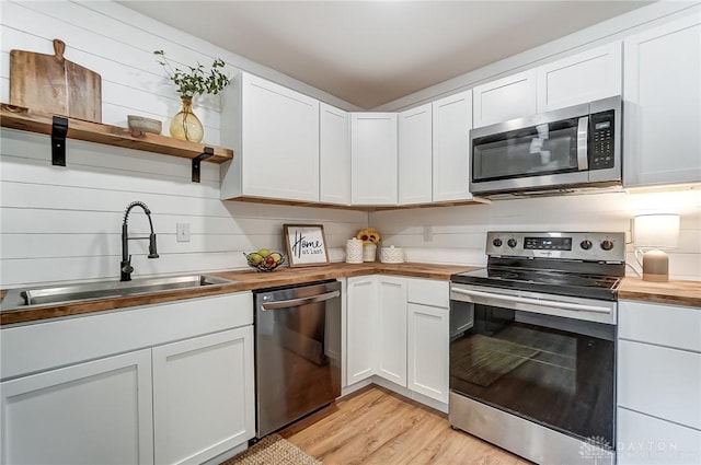 kitchen featuring white cabinetry, sink, butcher block counters, and stainless steel appliances