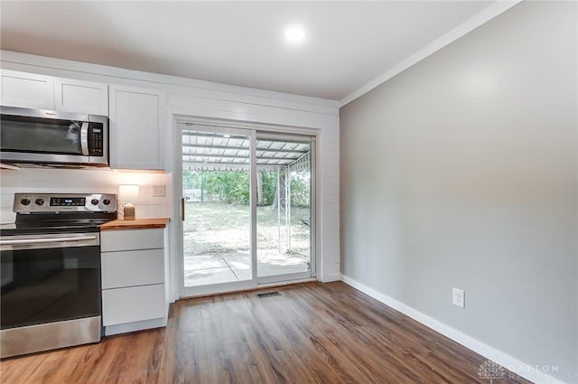 kitchen featuring butcher block counters, hardwood / wood-style floors, white cabinets, and stainless steel appliances