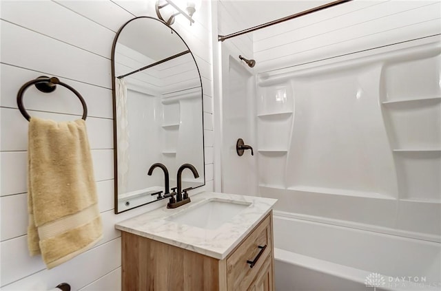 bathroom with wooden walls, vanity, and shower / bathtub combination