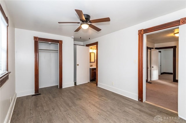 unfurnished bedroom featuring ceiling fan, ensuite bathroom, and dark hardwood / wood-style floors