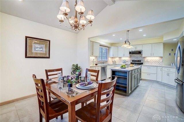 tiled dining area with lofted ceiling with beams, an inviting chandelier, and sink