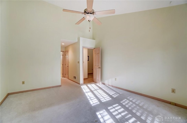 carpeted empty room featuring ceiling fan and high vaulted ceiling