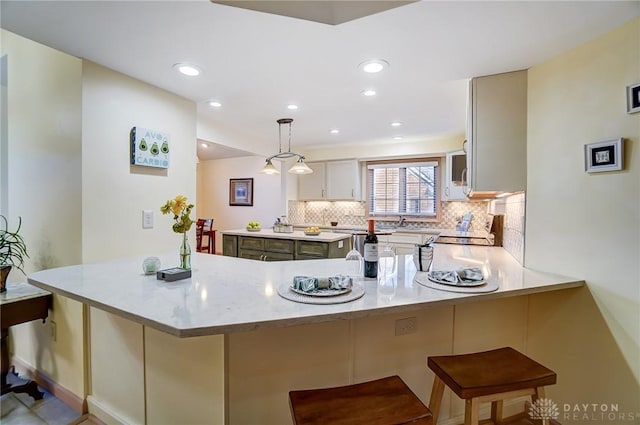 kitchen with kitchen peninsula, stove, a kitchen bar, decorative light fixtures, and white cabinetry