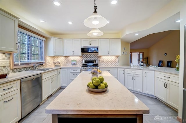 kitchen with decorative backsplash, appliances with stainless steel finishes, sink, pendant lighting, and a center island