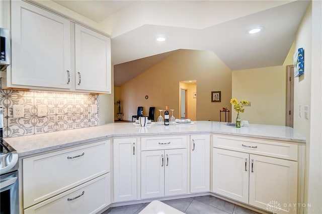 kitchen featuring kitchen peninsula, tasteful backsplash, and white cabinets