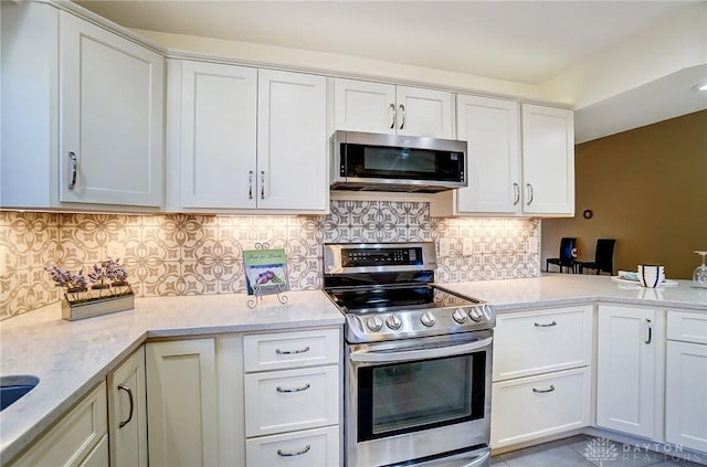 kitchen featuring backsplash, white cabinets, light stone countertops, light tile patterned floors, and appliances with stainless steel finishes