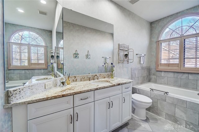 bathroom featuring tile patterned flooring, vanity, toilet, and tiled tub