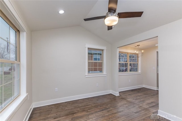 empty room with ceiling fan with notable chandelier, dark wood-type flooring, and vaulted ceiling