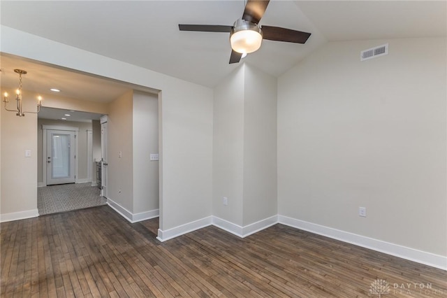 spare room with ceiling fan with notable chandelier, dark hardwood / wood-style flooring, and vaulted ceiling