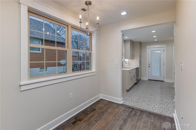 unfurnished dining area with dark hardwood / wood-style flooring, a notable chandelier, and sink