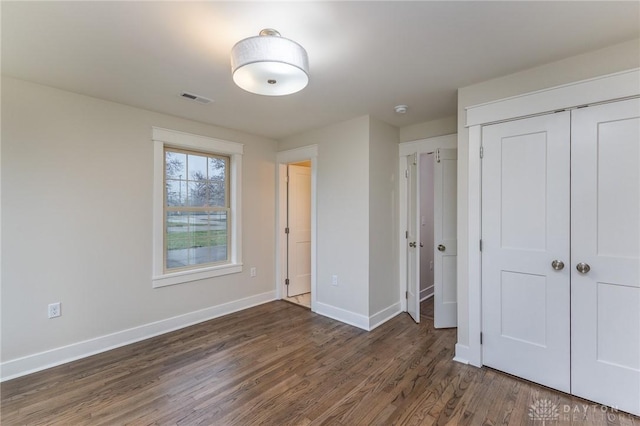 unfurnished bedroom featuring a closet and dark wood-type flooring