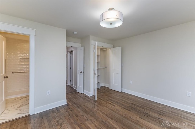 unfurnished bedroom with ensuite bathroom and dark hardwood / wood-style flooring