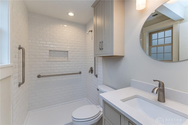 bathroom featuring vanity, toilet, and a tile shower