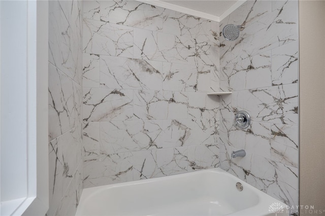 bathroom with ornamental molding and tiled shower / bath