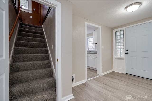 entrance foyer with sink, a textured ceiling, and light hardwood / wood-style flooring