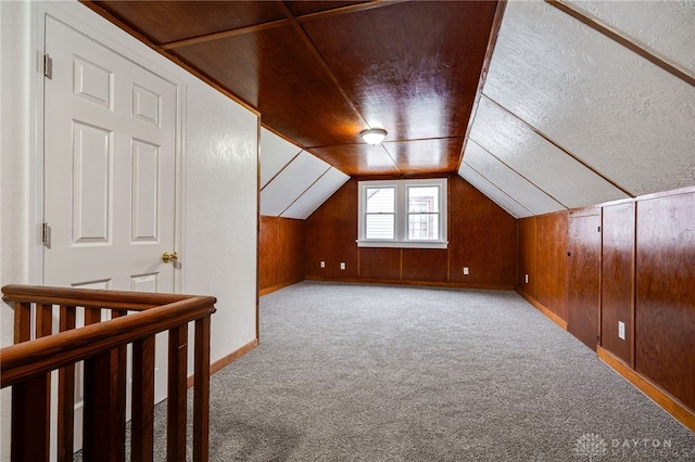 additional living space featuring wooden walls, a textured ceiling, vaulted ceiling, light carpet, and wood ceiling