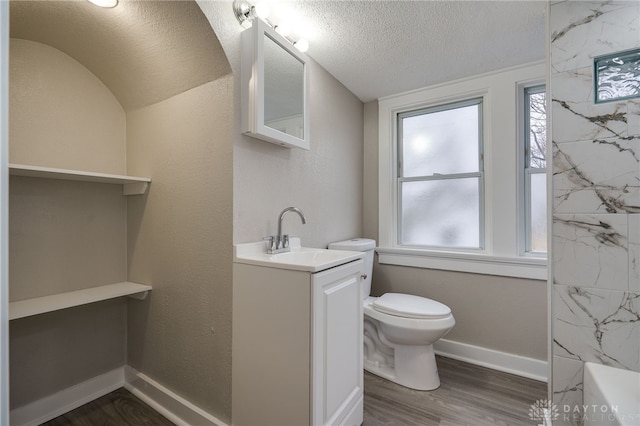 bathroom featuring a textured ceiling, vanity, hardwood / wood-style flooring, and toilet