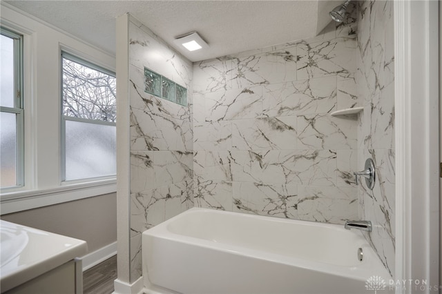 bathroom with vanity, hardwood / wood-style floors, a textured ceiling, and tiled shower / bath