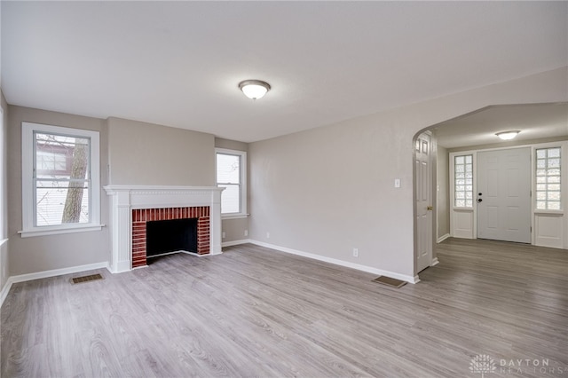 unfurnished living room featuring light hardwood / wood-style floors and a brick fireplace