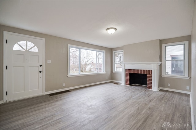 unfurnished living room featuring hardwood / wood-style floors and a brick fireplace