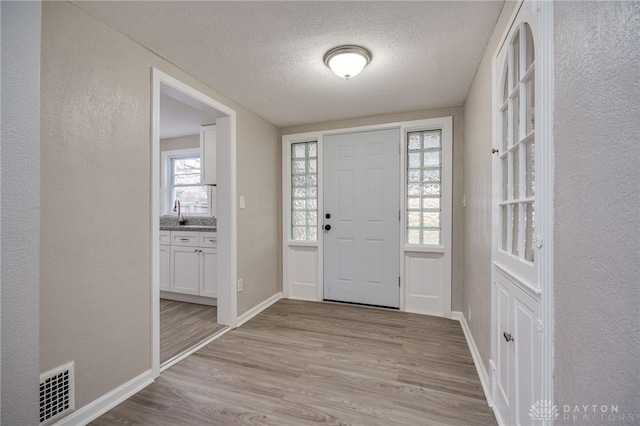 foyer entrance with a textured ceiling and light hardwood / wood-style flooring