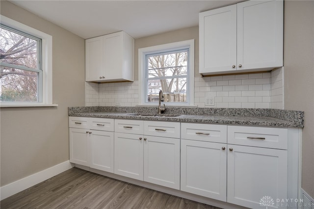 kitchen featuring sink, tasteful backsplash, light hardwood / wood-style flooring, stone countertops, and white cabinets