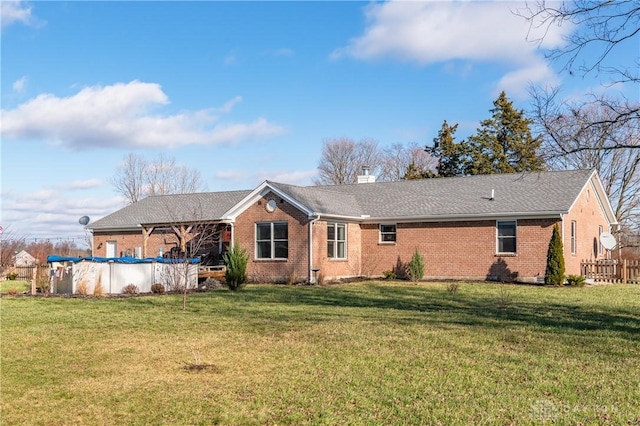 rear view of property featuring a lawn and a covered pool