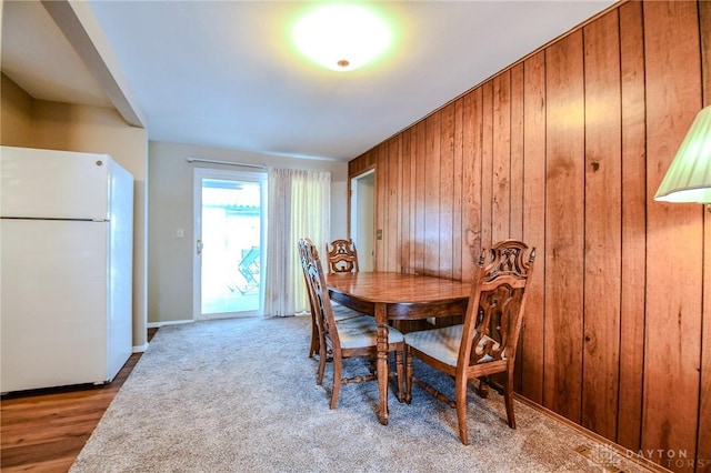 carpeted dining area with wood walls