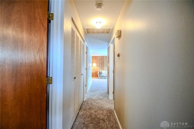 hall with light carpet and wooden walls