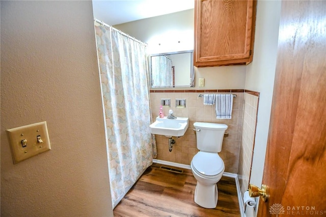 bathroom featuring wood-type flooring, toilet, tile walls, and sink