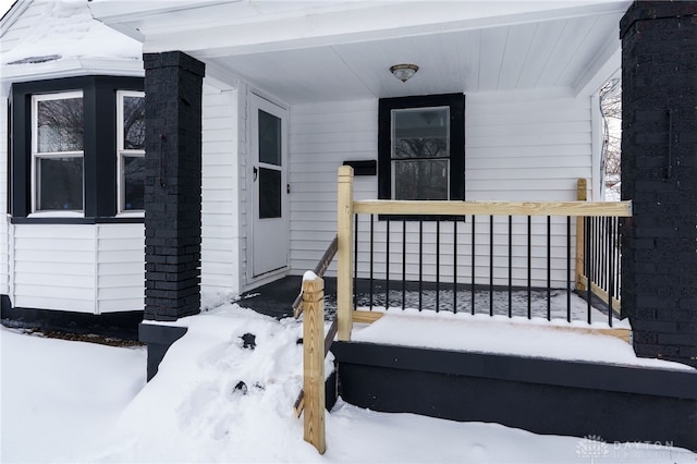 snow covered property entrance featuring covered porch