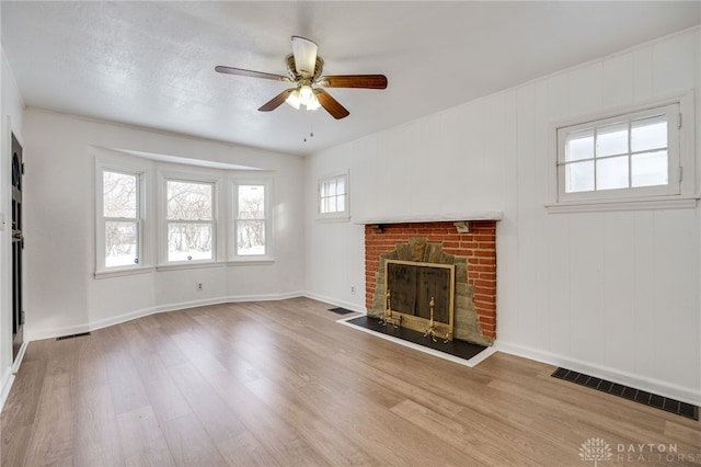 unfurnished living room with hardwood / wood-style flooring, ceiling fan, and a fireplace