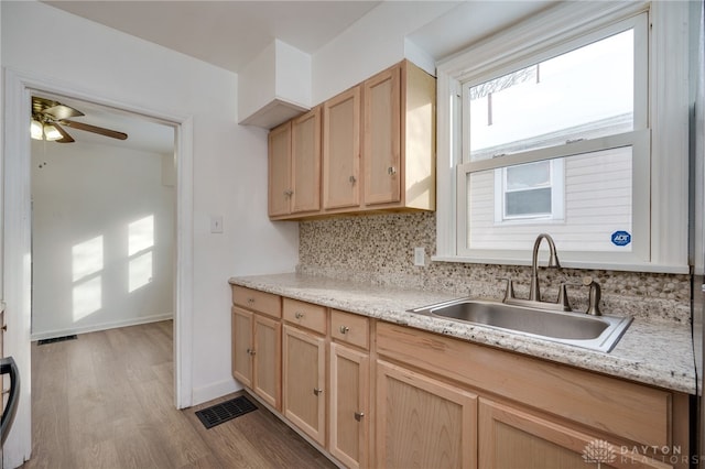 kitchen featuring light brown cabinets, sink, ceiling fan, decorative backsplash, and light hardwood / wood-style floors