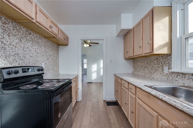 kitchen featuring backsplash, light brown cabinets, stainless steel range with electric stovetop, and light hardwood / wood-style flooring