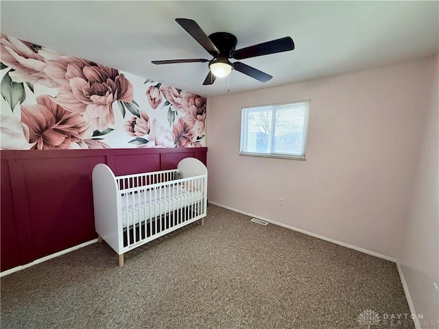 unfurnished bedroom featuring carpet flooring, ceiling fan, and a crib