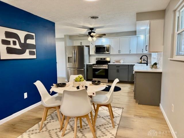 dining space featuring a textured ceiling, light hardwood / wood-style floors, ceiling fan, and sink