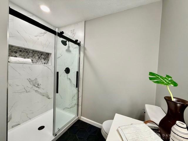 bathroom featuring tile patterned flooring, toilet, and a shower with shower door