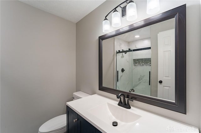 bathroom featuring vanity, a shower with shower door, a textured ceiling, and toilet