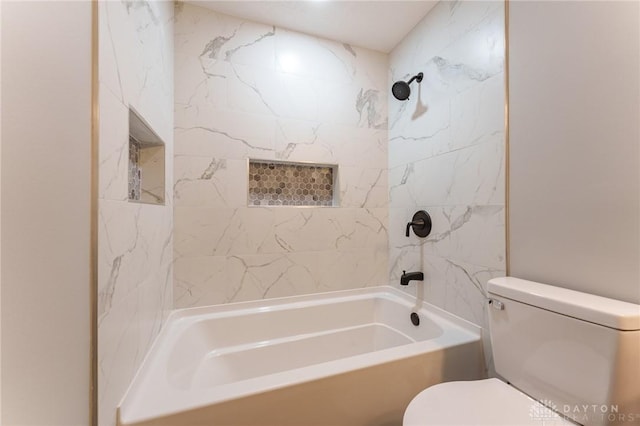 bathroom featuring tiled shower / bath combo and toilet