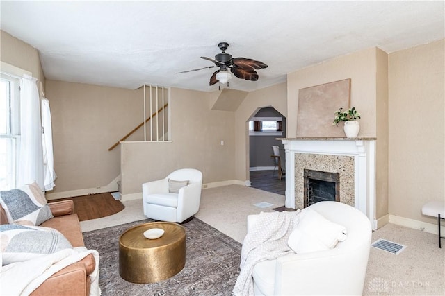 carpeted living room with a fireplace and ceiling fan