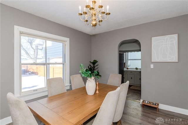 dining space featuring a textured ceiling, dark wood-type flooring, a wealth of natural light, and a chandelier