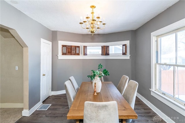 dining space featuring a textured ceiling, a notable chandelier, and dark wood-type flooring