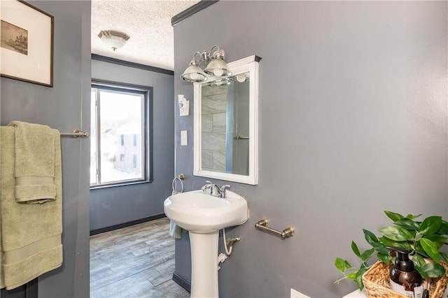 bathroom with sink, wood-type flooring, a textured ceiling, and crown molding