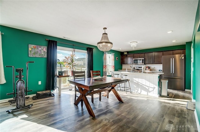 dining area with hardwood / wood-style floors and a notable chandelier