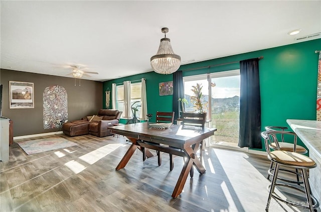 dining area with hardwood / wood-style flooring and ceiling fan with notable chandelier