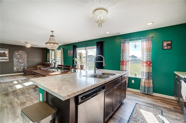 kitchen featuring sink, stainless steel dishwasher, plenty of natural light, decorative light fixtures, and a kitchen island with sink