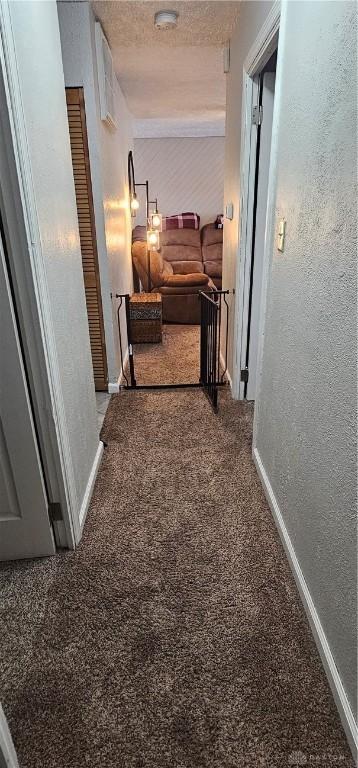 hall featuring carpet flooring and a textured ceiling